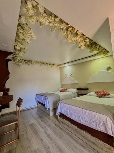 two beds in a room with flowers on the ceiling at Vicalis Hotel, Villas y Glamping in San Sebastian Xolalpa