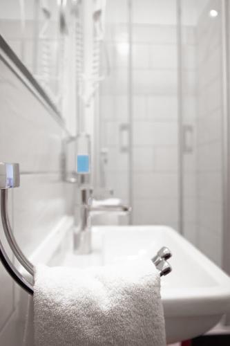 a white bathroom with a sink and a towel at Hotel Trierer Hof in Koblenz