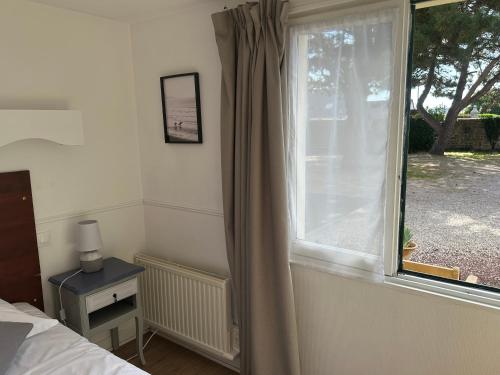 a bedroom with a window with a view of a yard at Logis Hôtel La Demeure du Perron in Quettehou