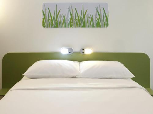 a bed with white sheets and two lights on it at ibis budget BH Afonso Pena Savassi in Belo Horizonte