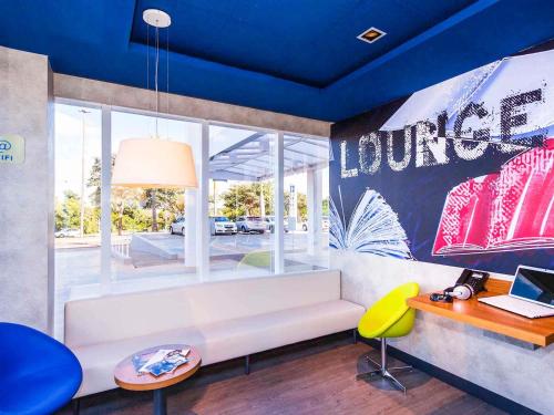 ein Wohnzimmer mit einem weißen Sofa und einem Schreibtisch in der Unterkunft ibis budget Campo Grande in Campo Grande