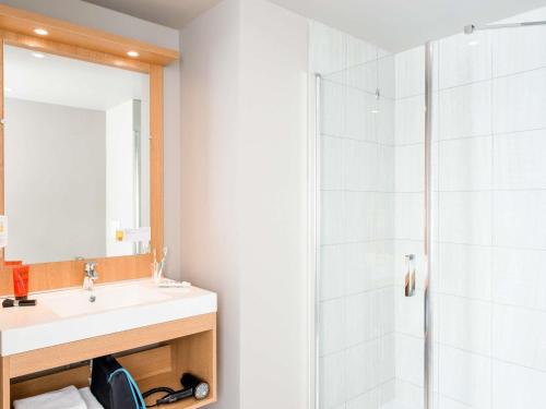 a bathroom with a shower and a sink and a mirror at Aparthotel Adagio Access Paris Massy Gare in Massy
