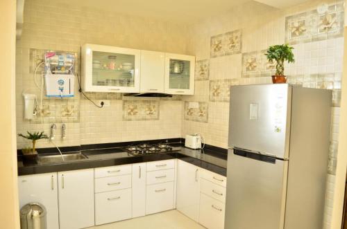 eine Küche mit weißen Schränken und einem Kühlschrank in der Unterkunft Rk Stay 2bhk Balewadi Highstreet Fully Furnished Premium in Pune