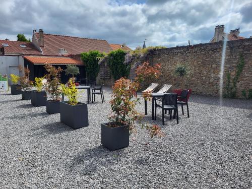 a row of tables and chairs and potted plants at Aparthotel Des 2 Caps in Ambleteuse