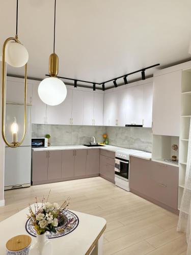 a large kitchen with white cabinets and a table at Light House apartments in Astana