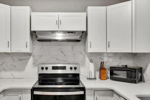 a kitchen with white cabinets and a stove and a microwave at 4 Bed Moroccan style, min to UNC, Kids Essentials, Crib, walk to Golf in Chapel Hill