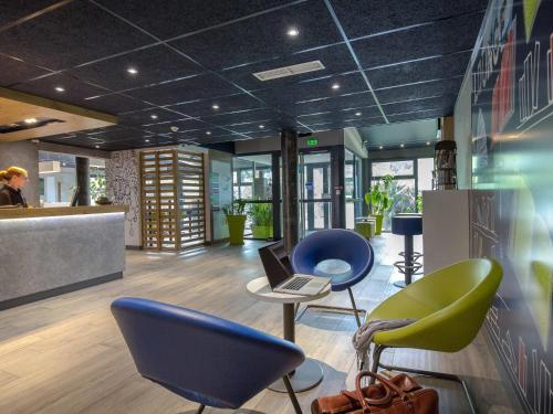 a lobby with chairs and a laptop on a table at ibis budget Brignoles Provence in Brignoles