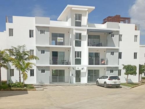 un bâtiment blanc avec une voiture garée devant dans l'établissement Peaceful Cottage, à Santiago de los Caballeros
