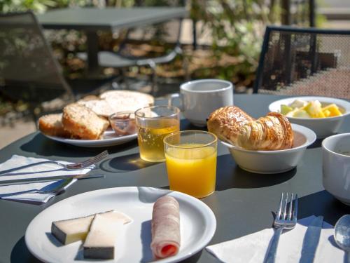 a table with plates of food and glasses of orange juice at ibis budget Brignoles Provence in Brignoles