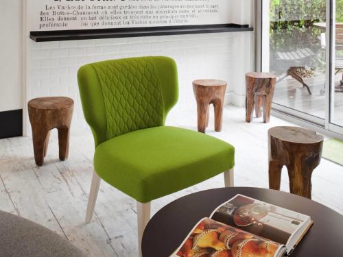 a green chair sitting in a room with a table at ibis Styles Paris Buttes Chaumont in Paris