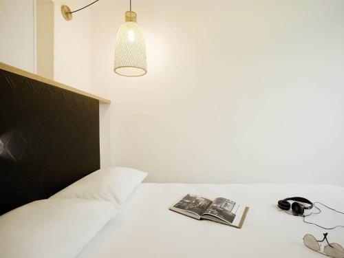 a bedroom with a bed with a book and a lamp at ibis Styles Paris Buttes Chaumont in Paris
