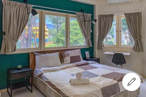 a bedroom with a large bed with two windows at Aurora Court Service Apartment in George Town