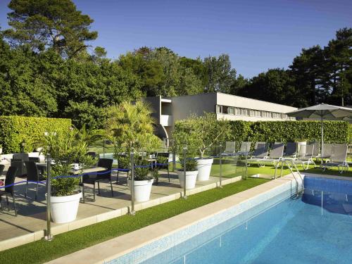 a swimming pool with chairs and plants next to a building at Mercure Orange Centre A7/A9 in Orange