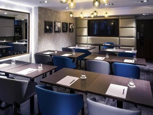 a restaurant with wooden tables and blue chairs at Mercure London Hyde Park Hotel in London