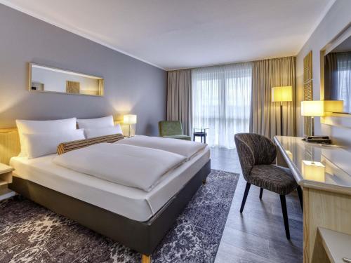 a hotel room with a large bed and a desk at Mercure Düsseldorf Kaarst in Kaarst