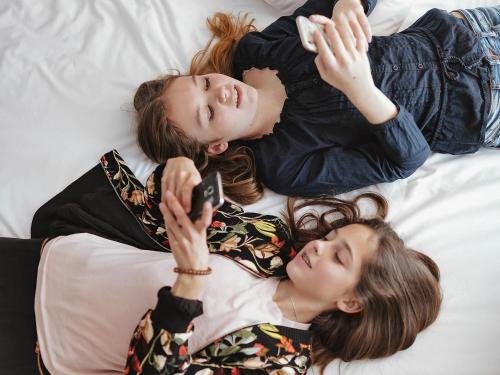 two girls laying on a bed looking at a cell phone at Mercure Düsseldorf Kaarst in Kaarst