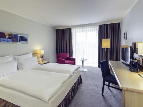 a hotel room with a bed and a desk at Mercure Düsseldorf Kaarst in Kaarst