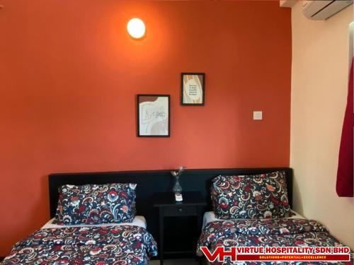 two beds in a room with an orange wall at Aurora Court Service Apartment in George Town