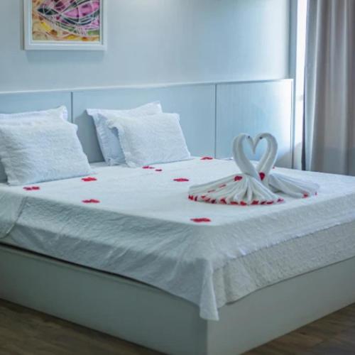 a white bed with two heart shaped towels on it at Nauticomar Resort All Inclusive - 23 a 30 de Nov in Porto Seguro