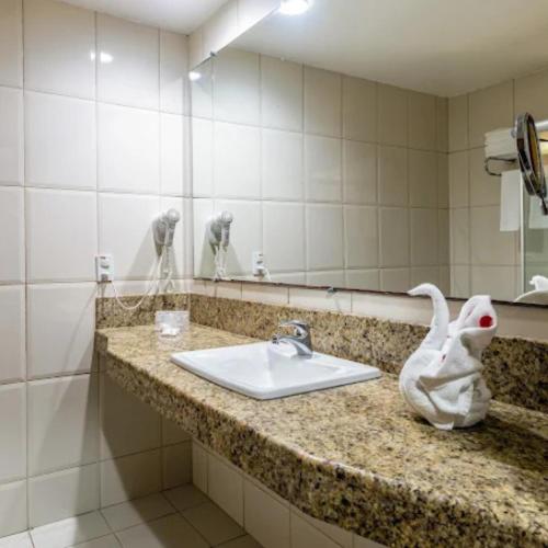 a bathroom with a sink and a mirror at Nauticomar Resort All Inclusive - 23 a 30 de Nov in Porto Seguro