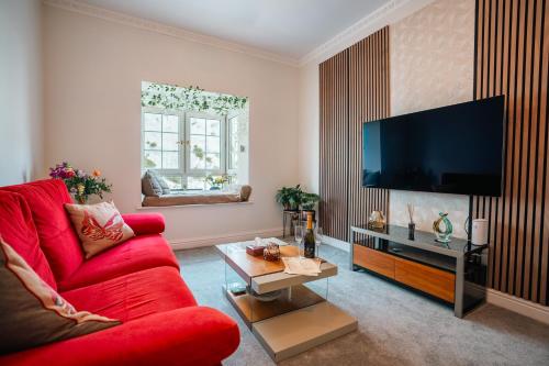 a living room with a red couch and a flat screen tv at Cozy 1BR Seaside Apt in Brighton Marina Village in Brighton & Hove