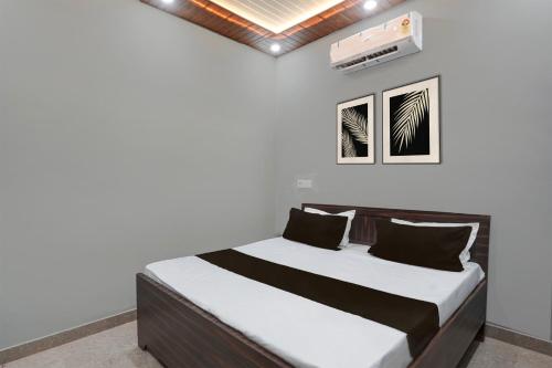 a bed in a room with a white wall at SPOT ON SHREE JI HOTEL AND RESTAURANT in Lonavala