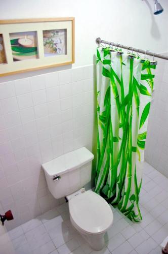 a bathroom with a toilet and a green shower curtain at Happy Ripples Beach Resort in Mabilao
