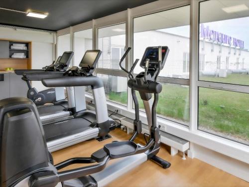 une salle de sport avec trois machines elliptiques et des fenêtres dans l'établissement Mercure Hannover Oldenburger Allee, à Hanovre