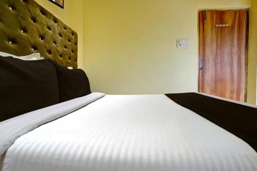 a bedroom with a white bed and a wooden door at Hotel O Royal Inn in Mumbai