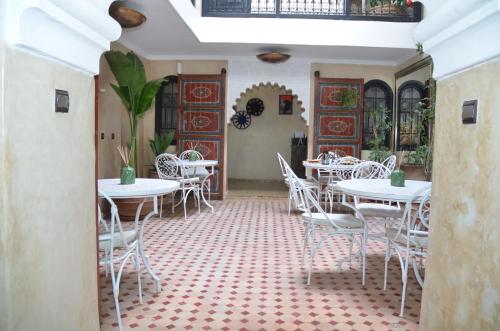 un restaurant avec des tables et des chaises blanches dans une salle dans l'établissement Riad dar serenity, à Marrakech