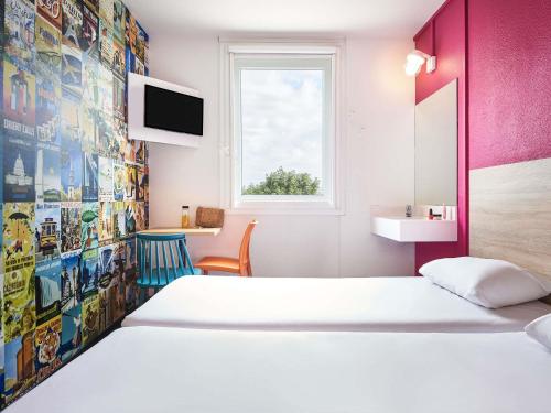 a bedroom with two beds and a pink wall at hotelF1 Beauvais in Beauvais