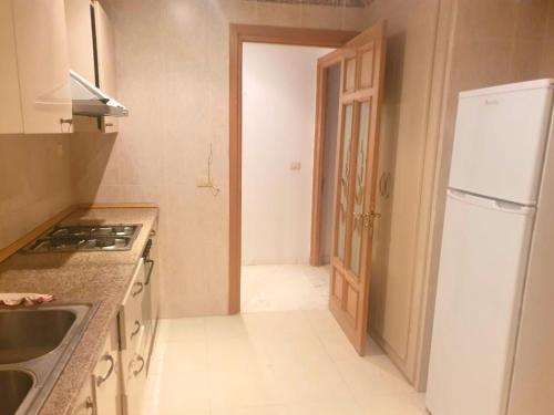 a kitchen with a sink and a refrigerator and a door at S2 Haut Standing à Ennasr - Grande Rue Hédi Nouira - Moderne avec Internet Haut Débit in Ariana