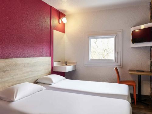 two beds in a room with a mirror and a window at hotelF1 Laval in Changé