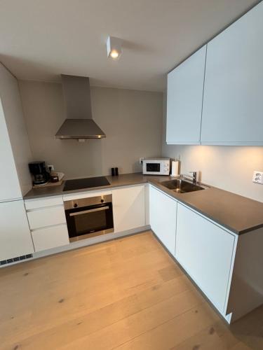 a kitchen with white cabinets and a sink at Ny leilighet i Ålesund med fantastisk utsikt in Ålesund