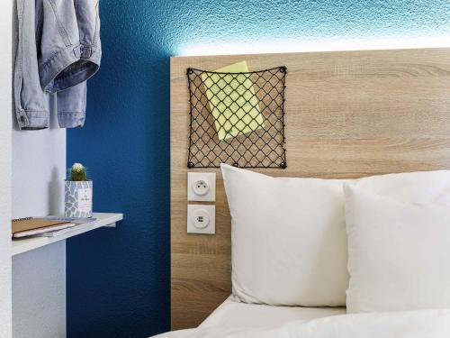 a bedroom with blue walls and a bed with white pillows at hotelF1 Les Ulis Courtaboeuf in Les Ulis