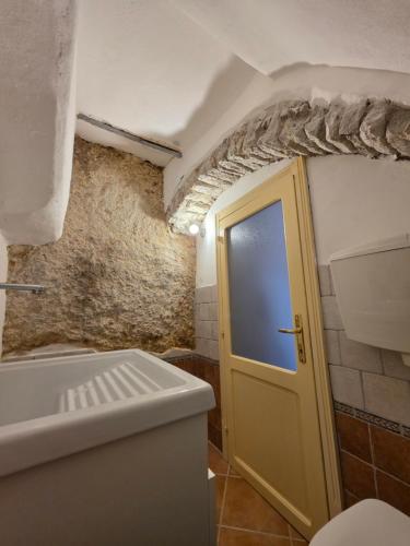 a bathroom with a yellow door and a brick wall at Domu Malaspina in Bosa