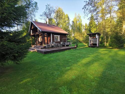 a small cabin in a yard with a green lawn at Ainja Puhkemaja in Viljandi