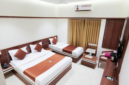 a hotel room with two beds and a chair at Hotel Laxmi Palace in Shirdi