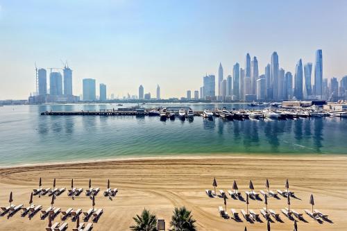 Una playa con un grupo de sillas y botes en el agua. en JBR Beach Front Apartment, en Dubái