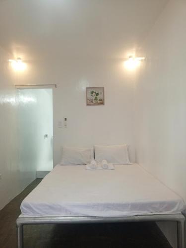 Una cama blanca con dos toallas encima. en Joan&Jimboy, en General Luna