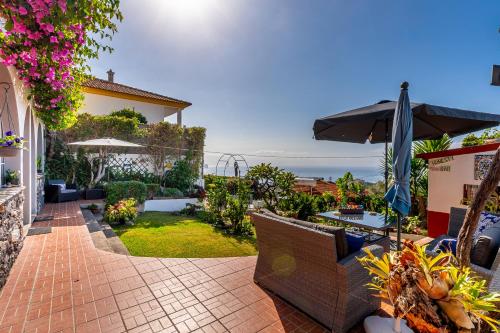 a patio with chairs and an umbrella and the ocean at Apartments Vista Oceano in Funchal