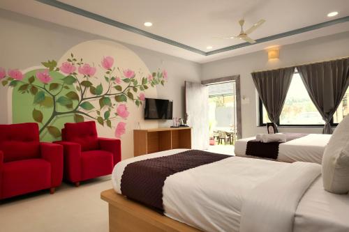 a bedroom with two beds and two chairs and a tv at Kunj - A Boutique Hotel By Shivaneel Hospitality in Pushkar