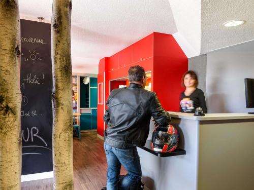 a man standing at a counter in front of a woman at hotelF1 La Rochelle Angoulins "Rénové" in Angoulins