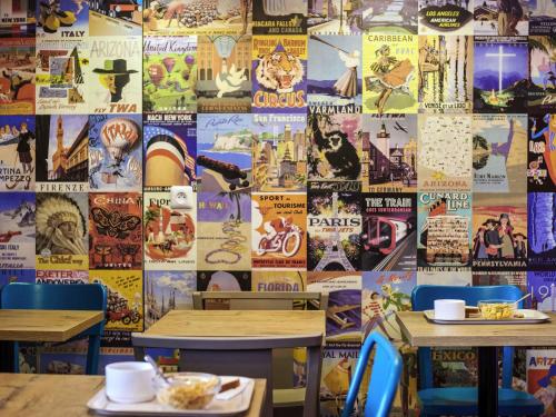 un restaurante con dos mesas y una pared cubierta de carteles en hotelF1 Saint Witz A1 Hôtel, en Saint-Witz