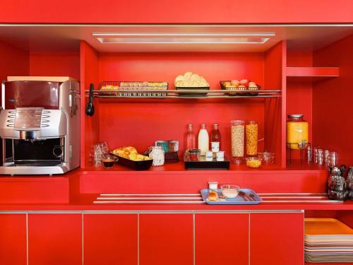 a kitchen with red walls and a counter with food at hotelF1 Chambéry Nord Rénové in Chambéry
