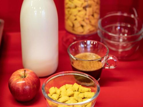 a table with a glass bowl of food and an apple and milk at hotelF1 Paris Saint Denis Université in Saint-Denis