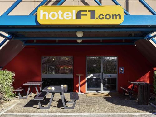 a hotel iguana with picnic tables in front of a building at hotelF1 Toulouse Aéroport in Blagnac