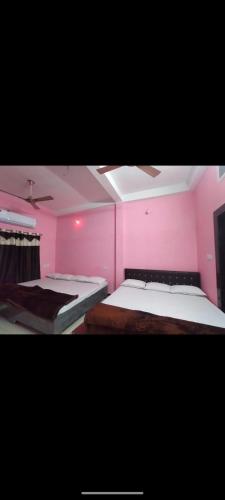 a pink room with two beds in it at Shikhar guest house 1 in Ujjain