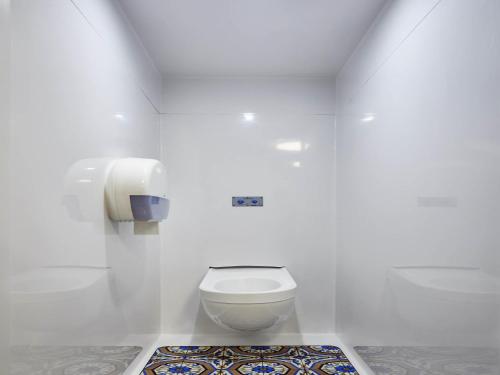 a white bathroom with a toilet and a rug at hotelF1 Lille Villeneuve d'Ascq in Villeneuve d'Ascq