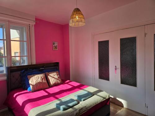 a bedroom with pink walls and a bed with pillows at Appartement de 50 M2 avec cuisine neuve plus terrasse de 40 m2 in Le Portel